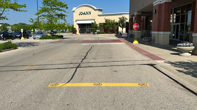 A painted yellow bar with No Shopping Carts symbol in the foreground and black stripes in the background at Town and Country Center in Arlington Heights (CARDINAL NEWS)