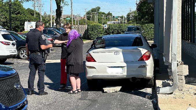 The driver and passenger speak with police after crashing into a building support at the Huntington Square strip mall on Rand Road near Hintz Road in Arlington Heights on Tuesday, June 11, 2024 (CARDINAL NEWS)