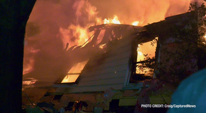 Fire scene shows a house fully-involved with flames behind a partially-collapsed wall on Overhill Drive in Lake Zurich on Tuesday, June 4, 2024 (Craig/CapturedNews)