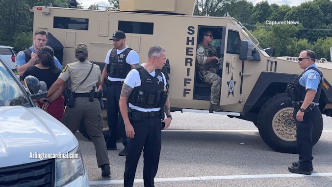 A female Illinois State Police trooper searches suspect Luisa Sanchez next to a Lake County Sheriff's Office armored vehicle on Route 14 immediately after her arrest at the Speedway gas station about 2:10 p.m. Tuesday, August 20, 2024 (CARDINAL NEWS)