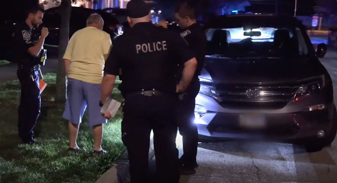 Arlington Heights police officers show the driver the shredded tire on his Honda Pilot at a traffic stop Saturday night, August 17, 2024 (CARDINAL NEWS).