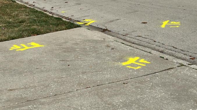 Police markings indicate where the wheels were located on the Ford Edge that was involved in the accident and came to rest straddled from the driveway, over the curb to the street (CARDINAL NEWS)