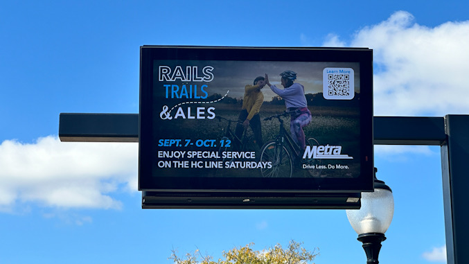 Message board (looking outbound away from Chicago) at downtown Arlington Heights Metra train station frozen on ad display on September 30, 2024 (CARDINAL NEWS)