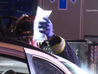 A Mount Prospect Fire Department firefighter/paramedic holds a medical IV solution bag during extrication of a patient in a white SUV on Rand Road north of Euclid Avenue in Arlington Heights after a head-on crash Monday night, September 2, 2024 (CARDINAL NEWS)