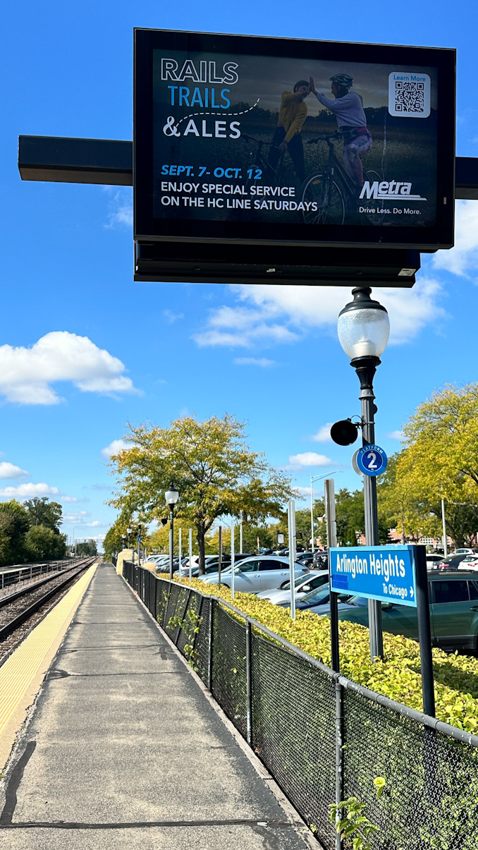 Message board (looking outbound away from Chicago) at downtown Arlington Heights Metra train station frozen on ad display on September 30, 2024 (CARDINAL NEWS)